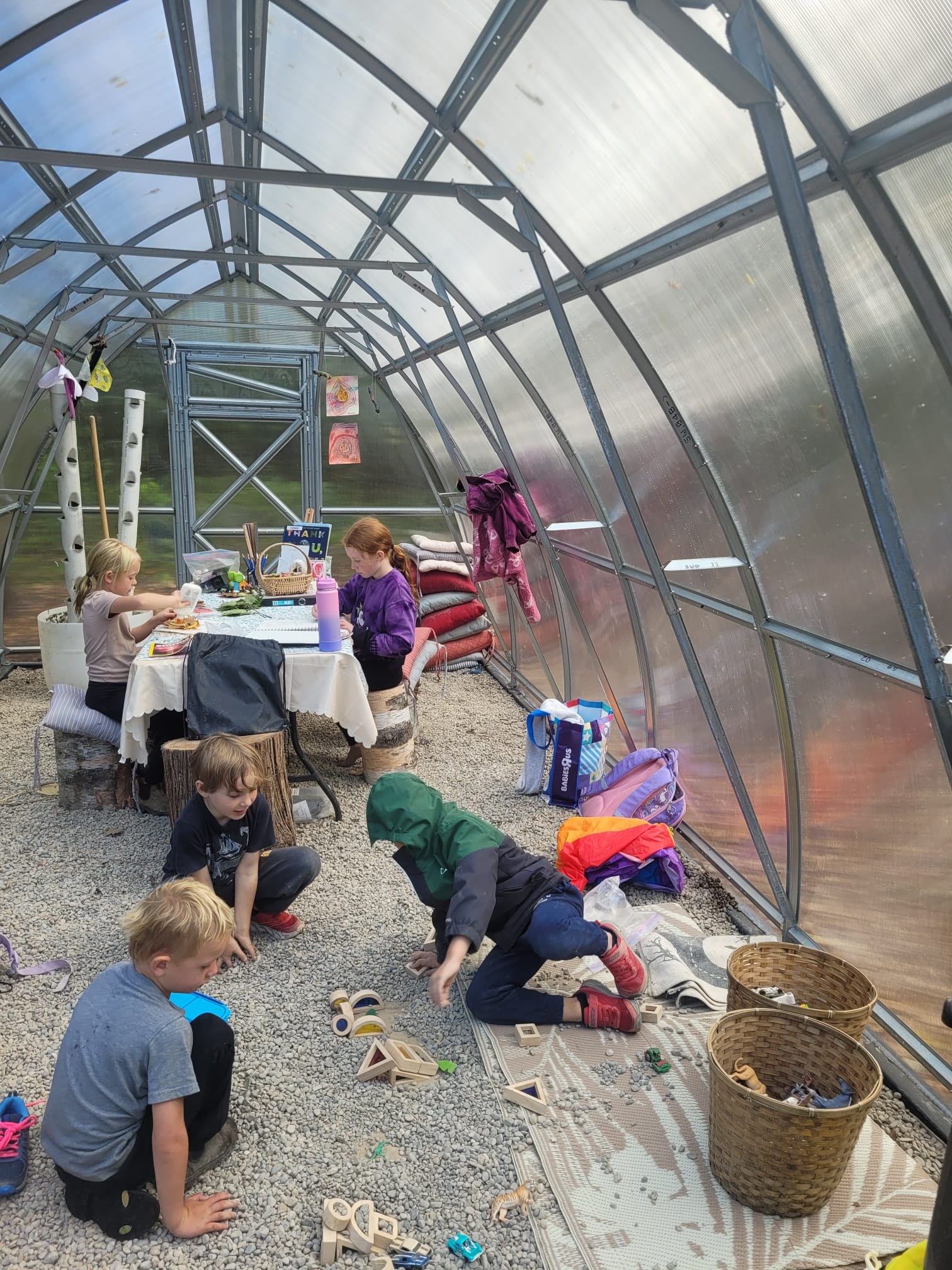Children playing and creating together inside the forest school greenhouse